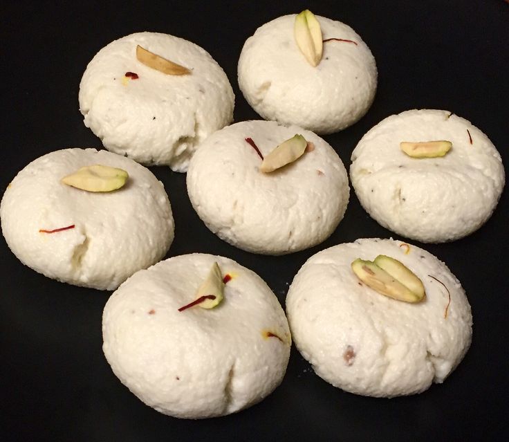 This may contain: six white cookies with pistachios on them sitting on a black table top