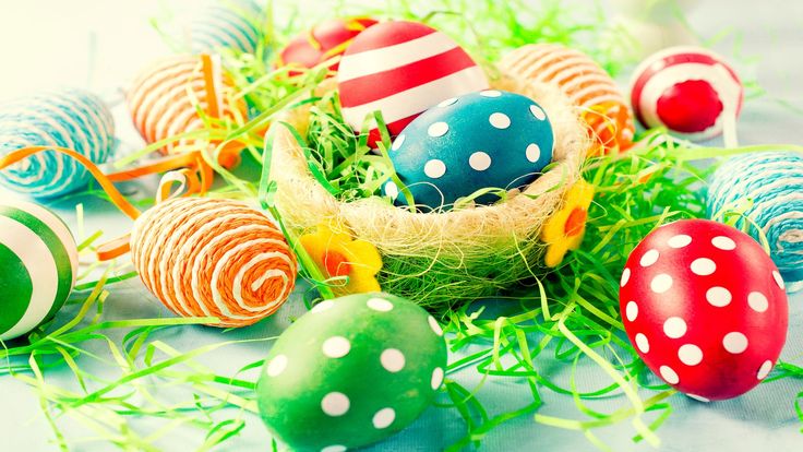 This may contain: an arrangement of colorful easter eggs in a basket with grass on the floor and white polka dots