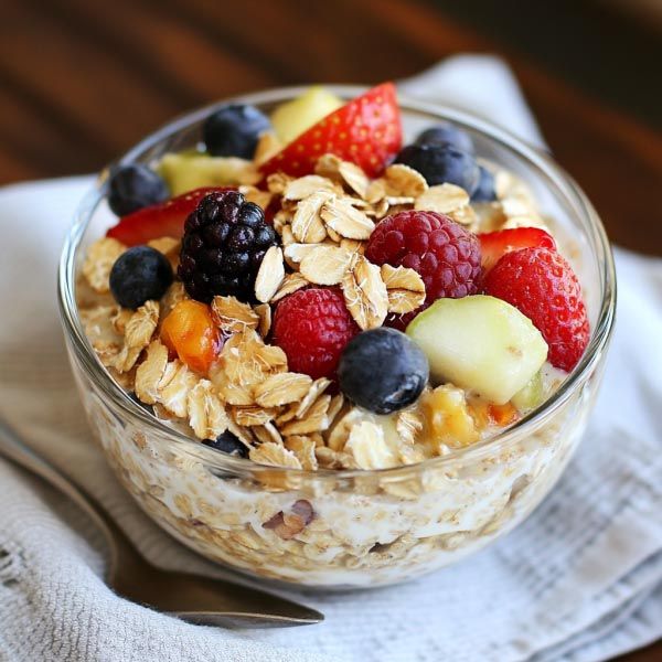 This may contain: a bowl of oatmeal with fruit and nuts is on a napkin next to a fork