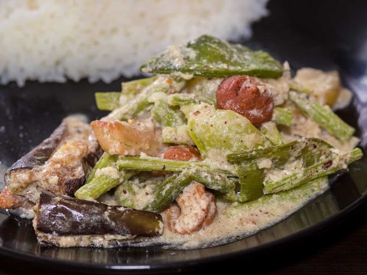 This may contain: a black plate topped with food next to rice