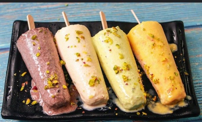 This may contain: four different types of ice cream on a black plate with toothpicks in them