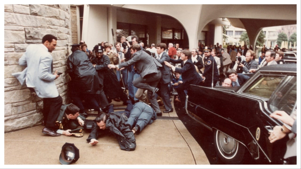 View of police officers and Secret Service agents as they dive to protect President Ronald Reagan amid a panicked crowd during an assassination attempt (by John Hinckley Jr) outside the Washington Hilton Hotel.
