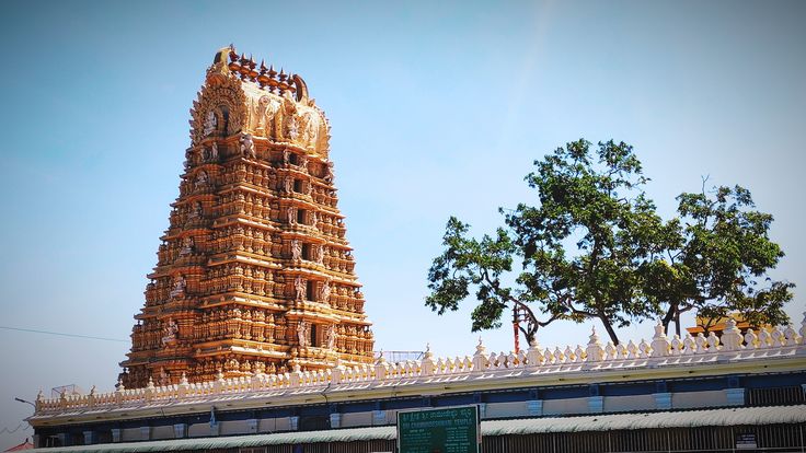 This may contain: a tall tower sitting next to a lush green tree