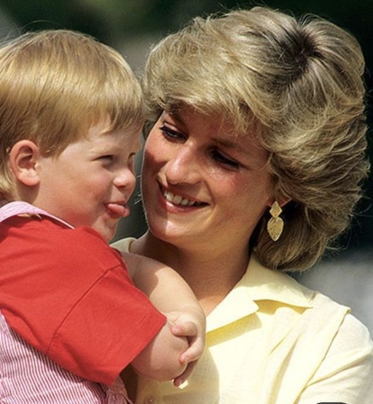 This may contain: a woman holding a small child in her arms